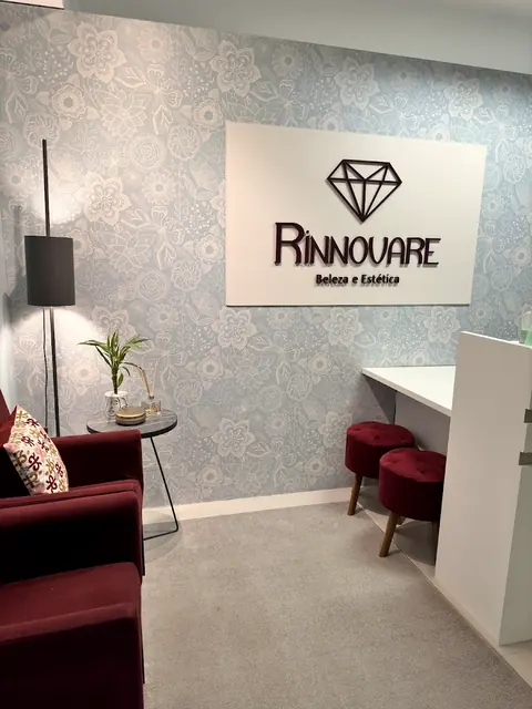 Recepção com o logo da Rinnovare na parede e poltronas bordô